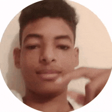 a close up of a young man 's face in a circle with his hand on his chin .