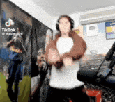 a person wearing headphones is dancing in front of a wall with a picture of diego maradona