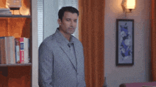 a man in a suit is standing in front of a bookshelf .
