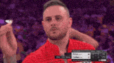 a man in a red shirt is holding a dart in front of a crowd