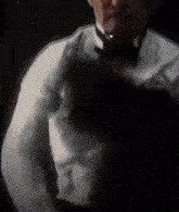 a man in a tuxedo and bow tie is standing in the dark holding a person .