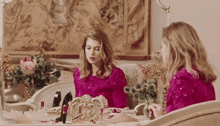 a woman in a pink dress is sitting at a table