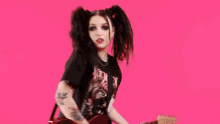 a girl with pigtails is holding a guitar and wearing a black shirt that says fleetwood mac