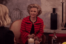 a woman in a red jacket is sitting at a table