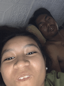 a man and a woman are laying in bed and the woman is making a funny face