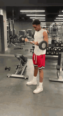 a man in red shorts is lifting a dumbbell in front of a mirror