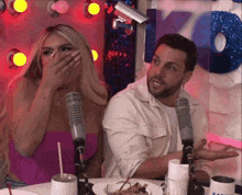 a man and a woman are sitting at a table in front of microphones and a sign that says k-drink