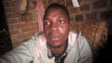 a man wearing a grey hoodie with pink laces looks at the camera