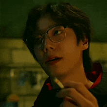 a close up of a person wearing glasses holding a cigarette .