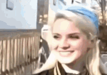 a close up of a woman wearing a blue headband and a school uniform smiling .