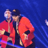 a man in a red jacket is dancing on stage