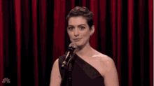 a woman in a black dress is singing into a microphone on a stage .