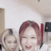 a couple of women are standing next to each other in a room and smiling .