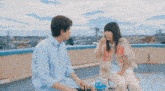 a man and a woman are sitting on a rooftop talking to each other with chinese writing on the bottom