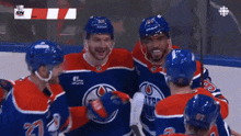 a group of edmonton oilers hockey players are hugging each other