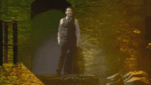 a man in a suit and tie stands in front of a stone wall in a dark room