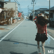 a woman walking down a street with the word ms on the bottom right
