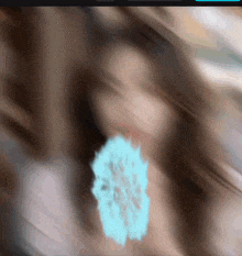 a blurry picture of a woman 's face with a blue flower in the foreground