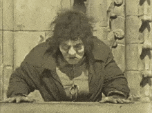 a black and white photo of a man crawling out of a hole in a building .