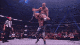 a wrestler is laying on the ground while a referee looks on during a match