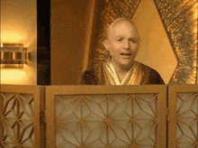a man in a robe stands behind a wooden partition