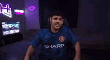 a man wearing headphones and a blue shirt with the word sharp on it .