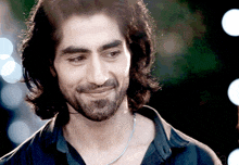 a man with long hair and a beard is smiling and wearing a black shirt