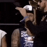 a man wearing a shirt that says thunder is standing next to another man .