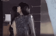 two women are standing next to each other in a room and looking at each other .