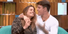 a man and a woman are sitting next to each other on a blue couch and laughing .