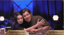 a man and a woman sitting at a table with a sign that says letters