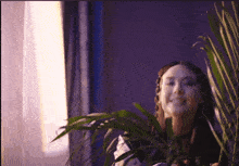 a woman stands in front of a plant with a sticker on it that says ' i '