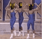 three men wearing blue overalls and white boots are dancing together