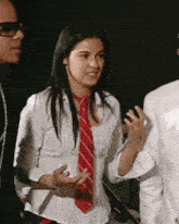 a woman wearing a white shirt and a red tie talks to a man