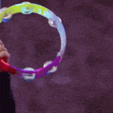 a person holding a colorful tambourine with a purple background