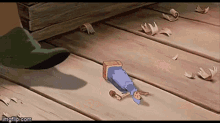 a cartoon character is laying on a wooden floor next to a green boot .