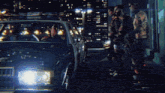 a group of people are standing around a police car at night