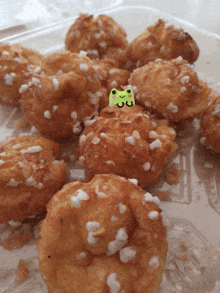 a green frog is sitting on top of a tray of food
