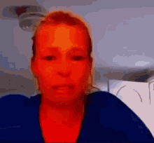 a woman with a red face is sitting in front of a fire alarm .