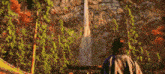 a man standing in front of a waterfall with trees in the background