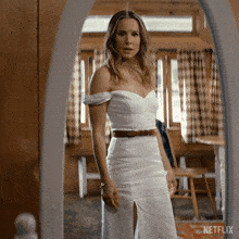 a woman in a white dress stands in front of a mirror with netflix written on the bottom right