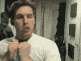 a man in a white shirt is tying a tie .