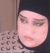 a close up of a woman wearing a hijab and makeup .