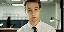 a young man in a white shirt and tie is making a funny face .
