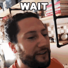 a man with a beard has the word wait above his face