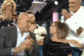 a man in a suit is kissing a woman on the cheek in a crowd of people .