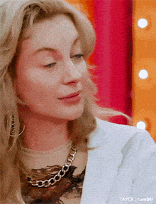 a close up of a woman wearing a white jacket and a gold necklace