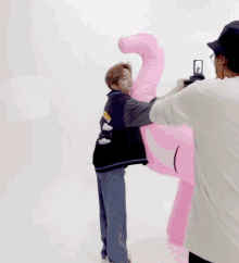 a man taking a picture of a pink flamingo with a good work sticker in the background