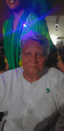 an older man wearing a white shirt with a green g on the front
