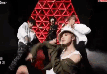 a group of people are dancing on a stage in front of a red and white triangle .